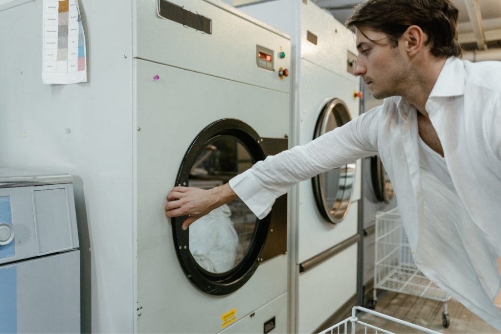 Hombre abriendo puerta de secadora de ropa